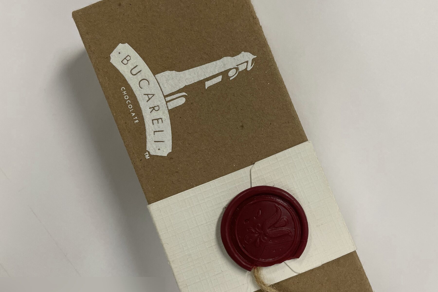 Close view of a Bucareli box: the white lighthouse mark printed on kraft board above the belly band.